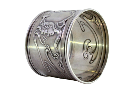  Argola de guardanapo com relevos femininos e laços envolvidos.